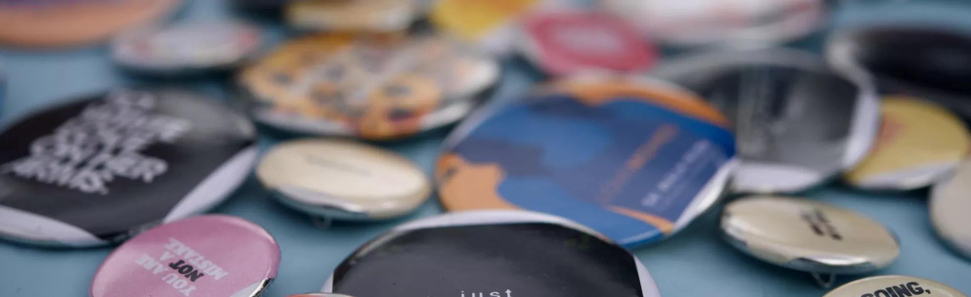 Close-up of several round pins with different phrases and words of encouragement on them.