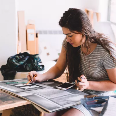 Student drawing on a large drawing pad in an art studio setting.