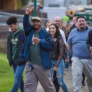 A group of Western staff walking towards the camera. The main in front of the line is making a peace sign at the camera.