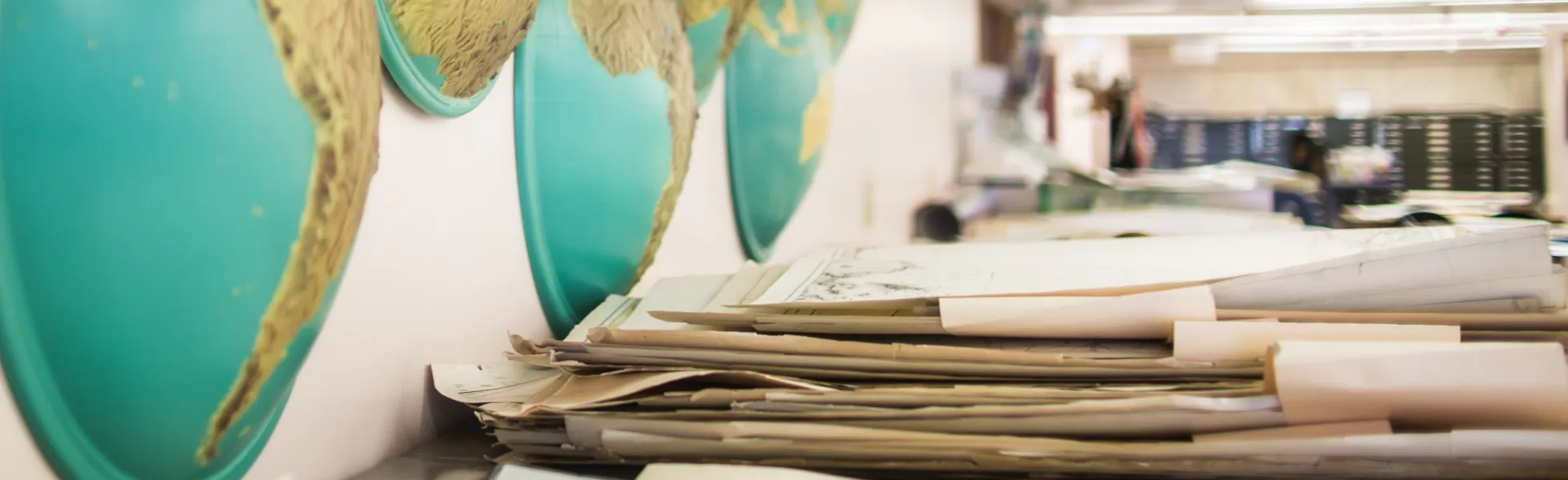 A desk with piles of maps in a large room.