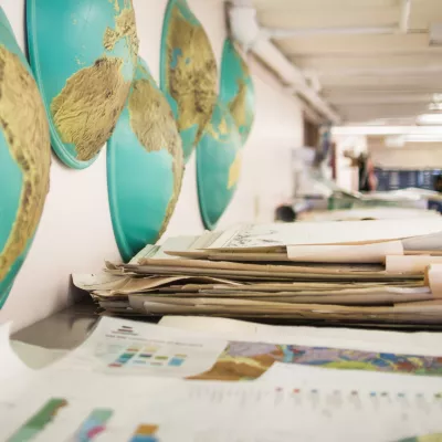 A desk with piles of maps in a large room.