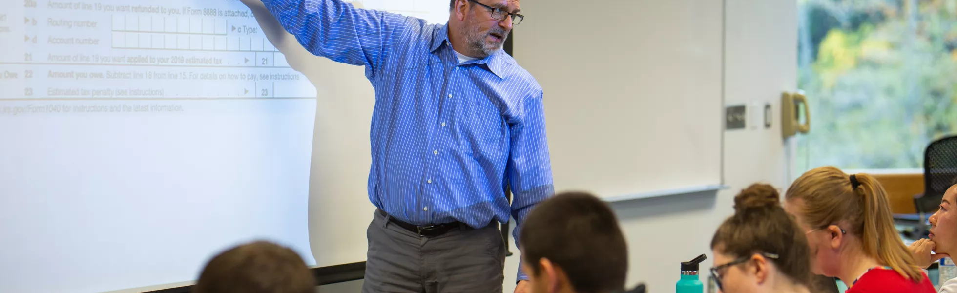 A professor lecturing about accounting concepts to a class.