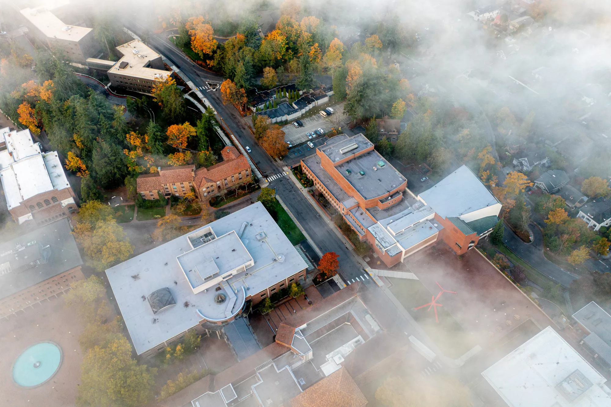 Aerial shot of Old Main on campus in fall with a misty fog covering much of campus.