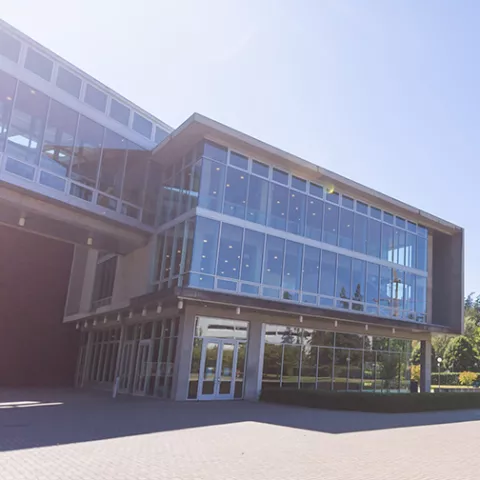 Academic Instruction Center, a modern square building with three floors and floor-to-ceiling windows on three sides
