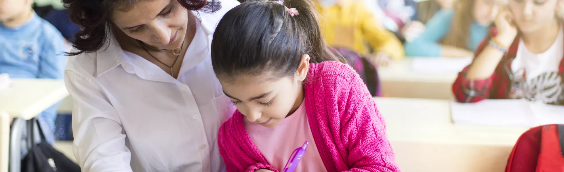 A teacher works closely with an elementary school student on a reading assignment.