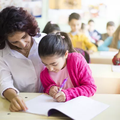 A teacher works closely with an elementary school student on a reading assignment.