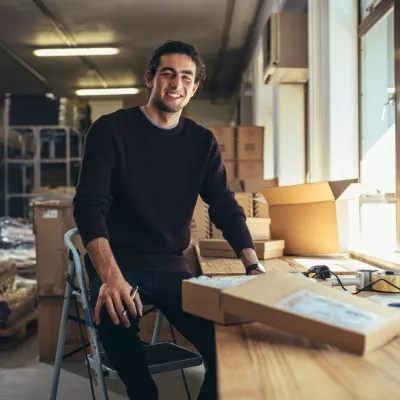 a person sitting in a warehouse with some packaging materials, processing orders.