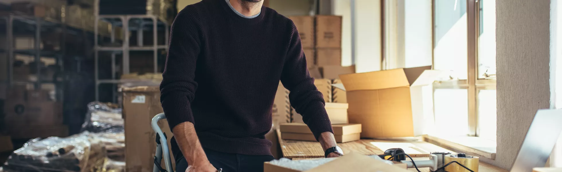 a person sitting in a warehouse with some packaging materials, processing orders.