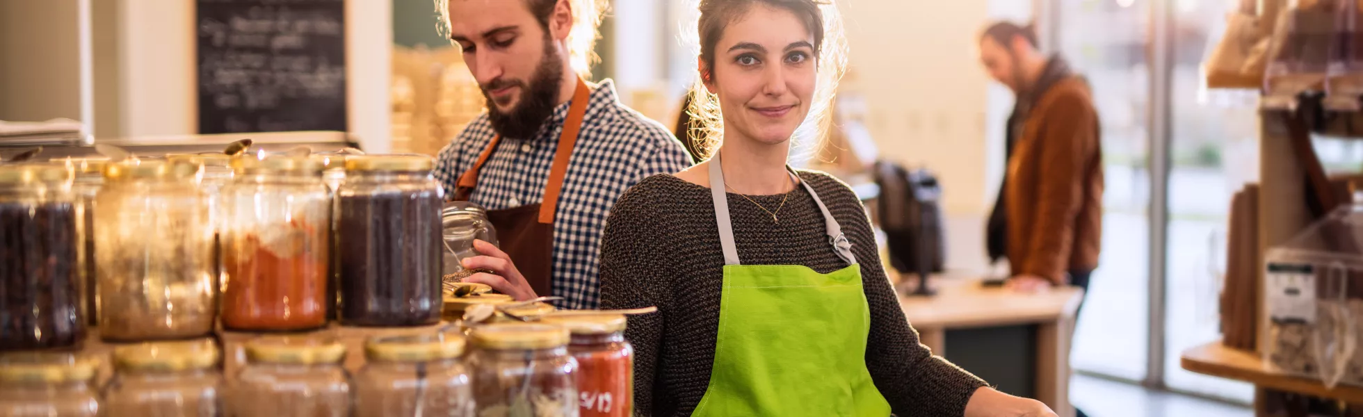Two store owners displaying food products in their business.