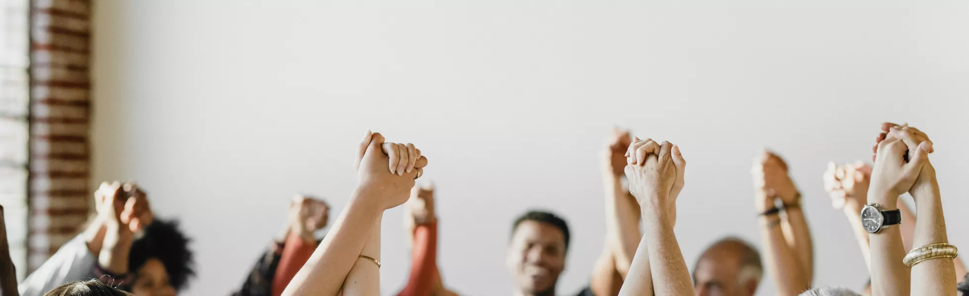 A room full of people holding each others hands up in the air.