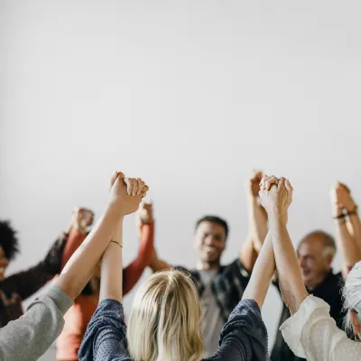 A room full of people holding each others hands up in the air.