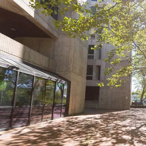 Arntzen Hall, a concrete building with floor to ceiling glass on the first floor.