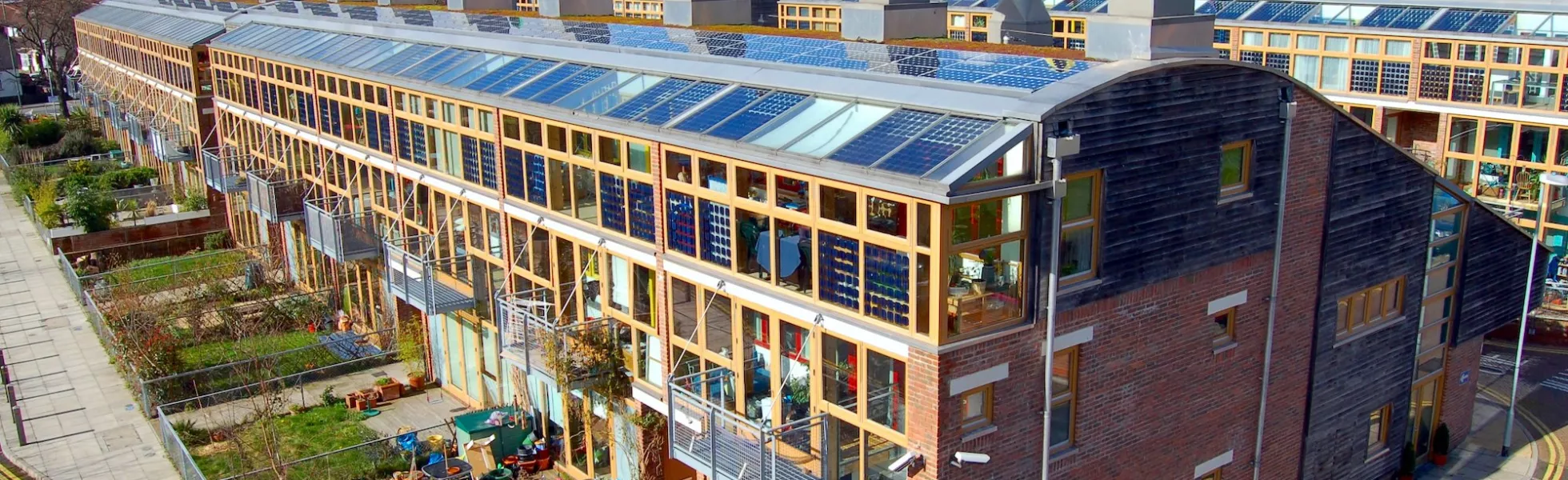 Large sustainable buildings with many windows, brick walls, and colorful wind cowls that circulate air. There is plenty of green space and sidewalks.