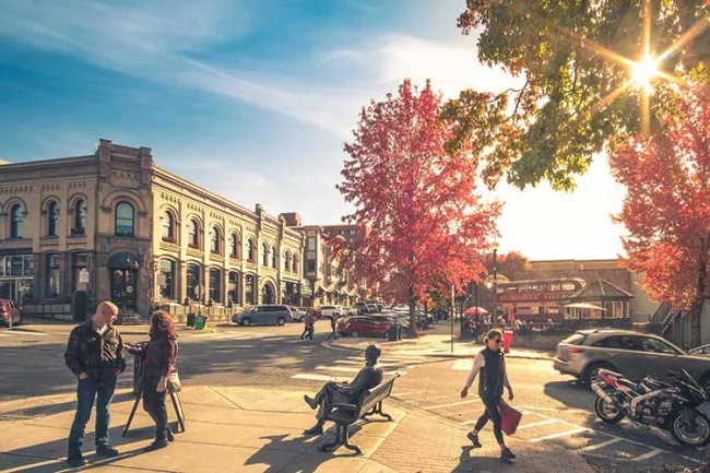 Downtown Fairhaven on a sunny day. Residents are milling about enjoying the sunshine and chatting with others in groups.