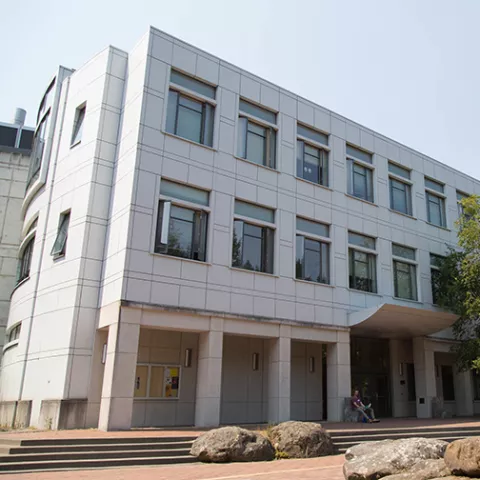 The Biology Building, a three story white stone building located on a brick plaza.
