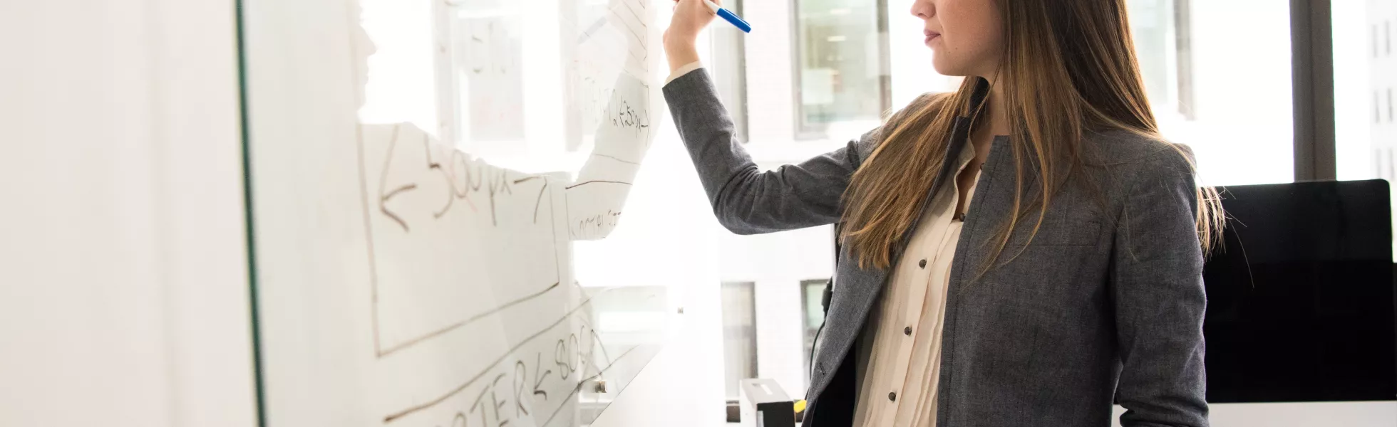 A person writing on a white board during a presentation.