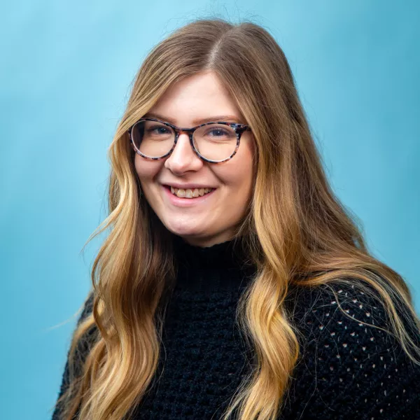  Caitlyn looks at the camera with a friendly smile, while sporting a black sweater and marble-pattern glasses.