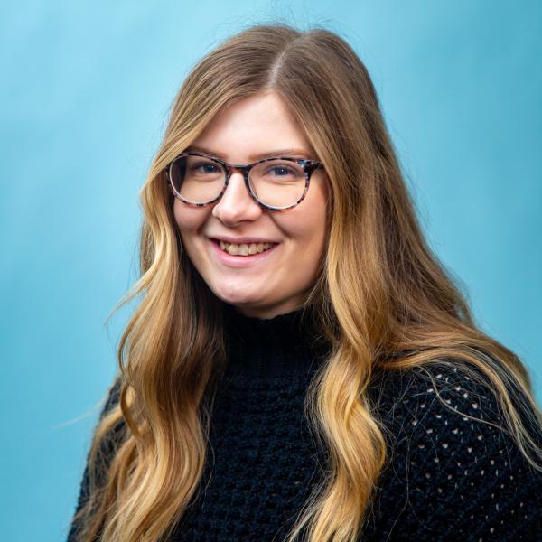  Caitlyn looks at the camera with a friendly smile, while sporting a black sweater and marble-pattern glasses.