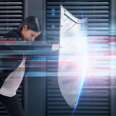 In a server stack, a person holds up a large shield to hold off a metaphorical cyberattack