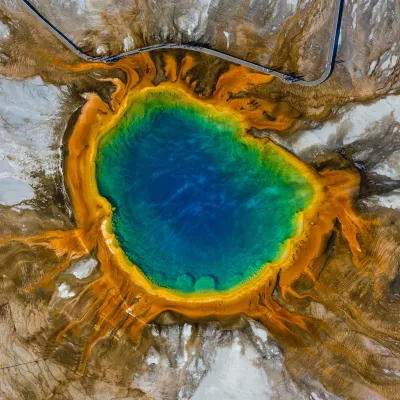 Aerial view of Grand Prismatic Spring in Yellowstone National Park. Huge rainbow colored hot spring in a field of salty white.