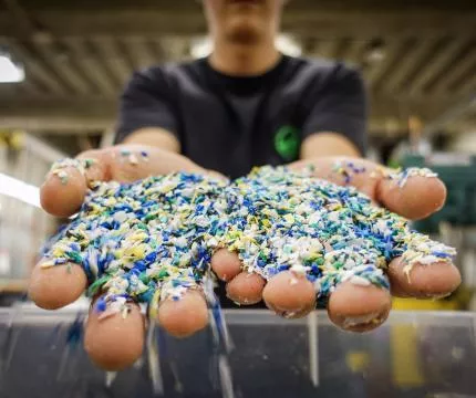 A student holding out plastic shavings in both hands.