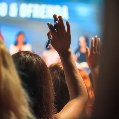 Back view of someone in an audience with their hand up