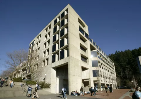 Student walk past Environmental Studies, a five-story concrete building.