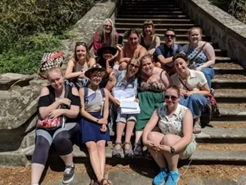A group of students sitting on steps in summertime.
