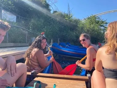 4 students sitting in canoes at the dock, 2 of them are holding paddles.