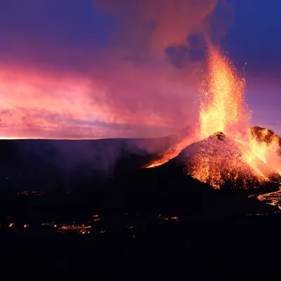 Icelandic volcano erupting lava against a beautiful pink and blue sunset.