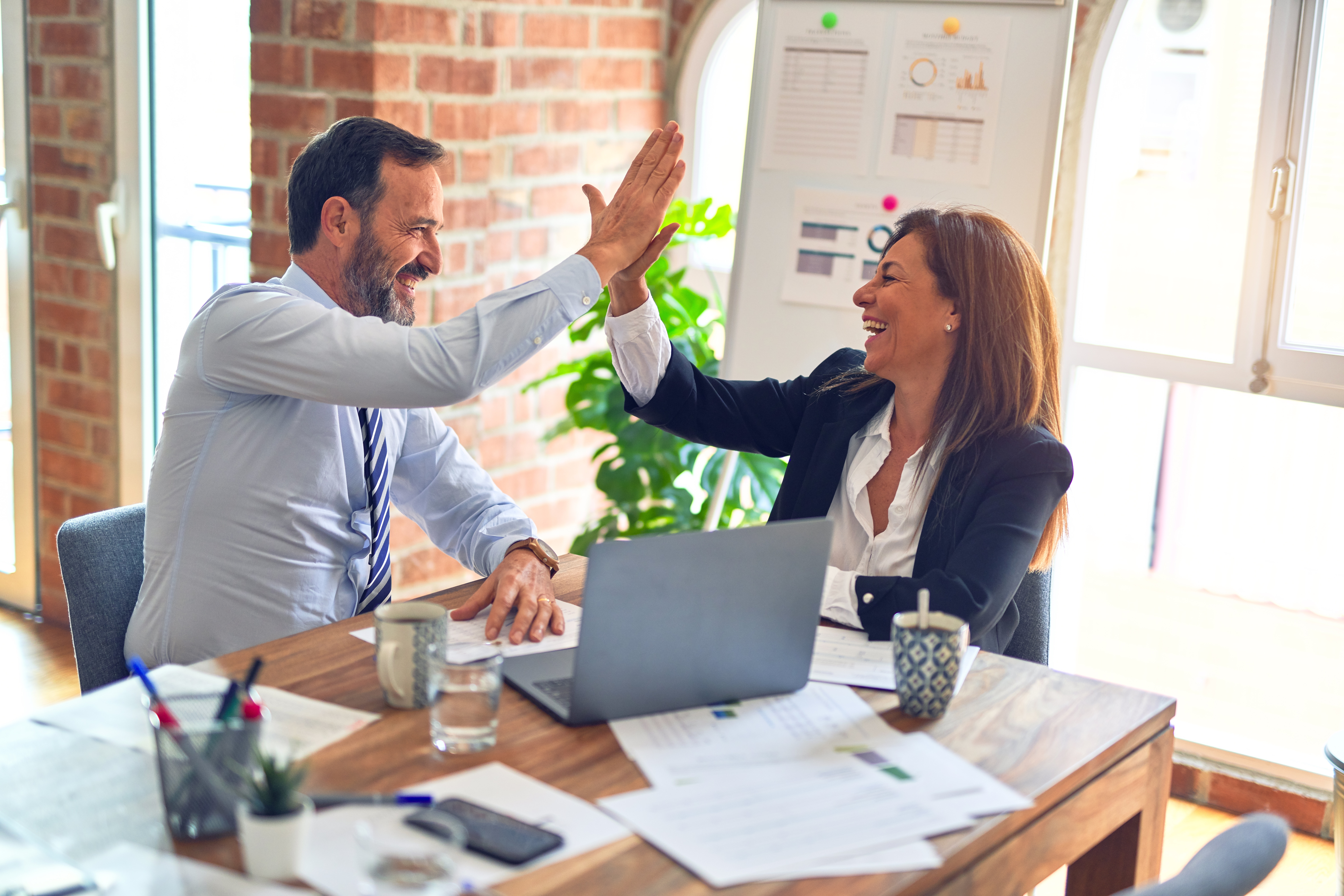 Two people in business attire giving a high five