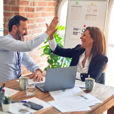 Two people in business attire giving a high five