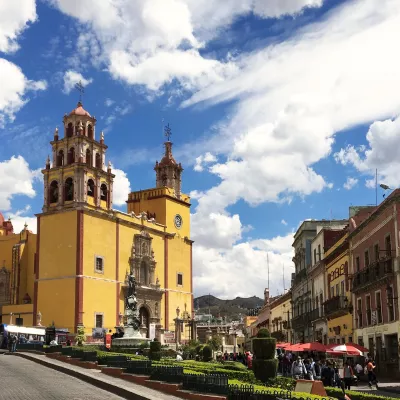 Streets of a city on a sunny day, with a yellow cathedral centered in shot