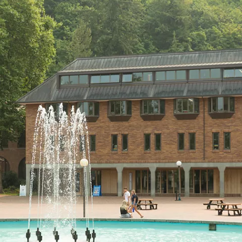 Miller Hall, a four story brick building, sits in a brick square with a large fountain in the center.