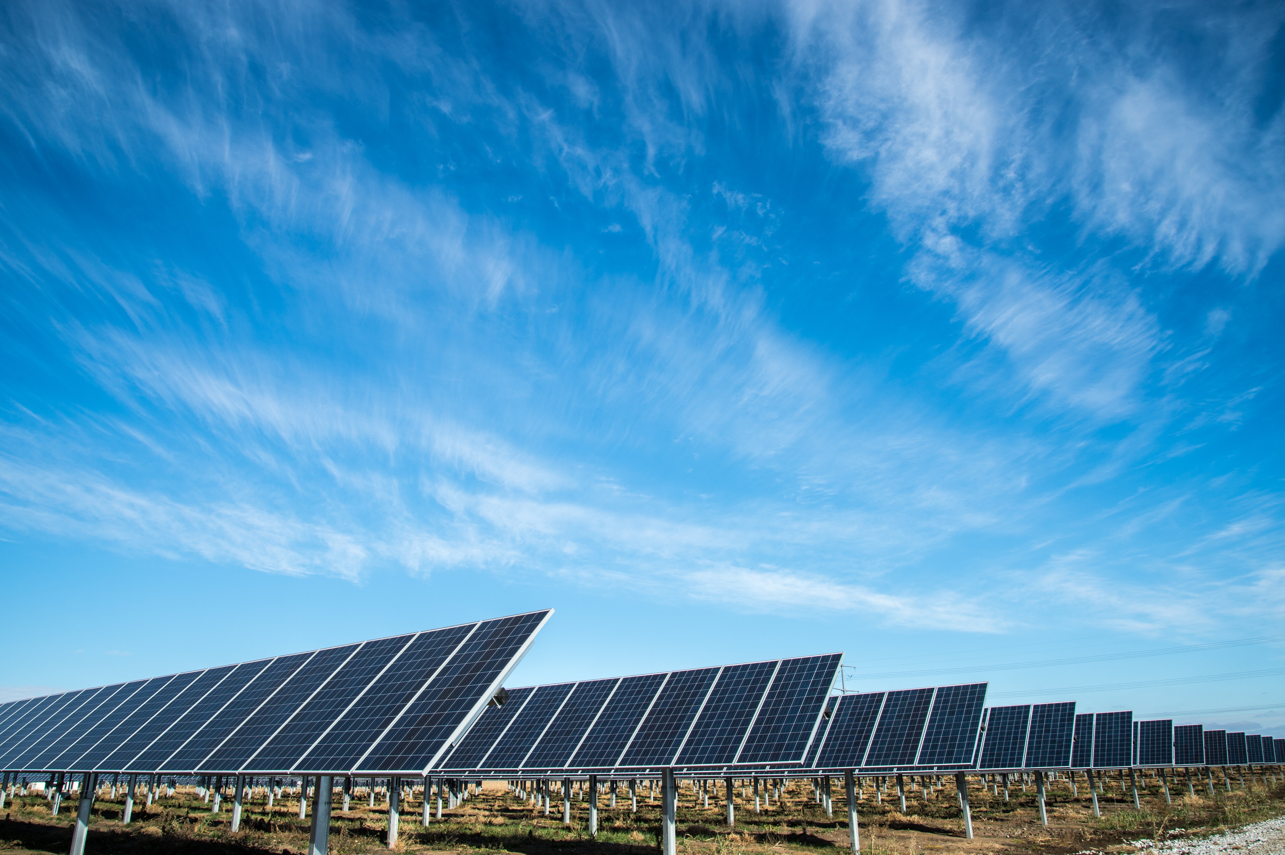 Solar panels against a lightly cloudy blue sky