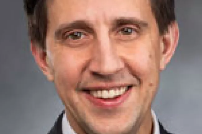 Representative Alex Ramel wears a button down shirt, tie and jacket
