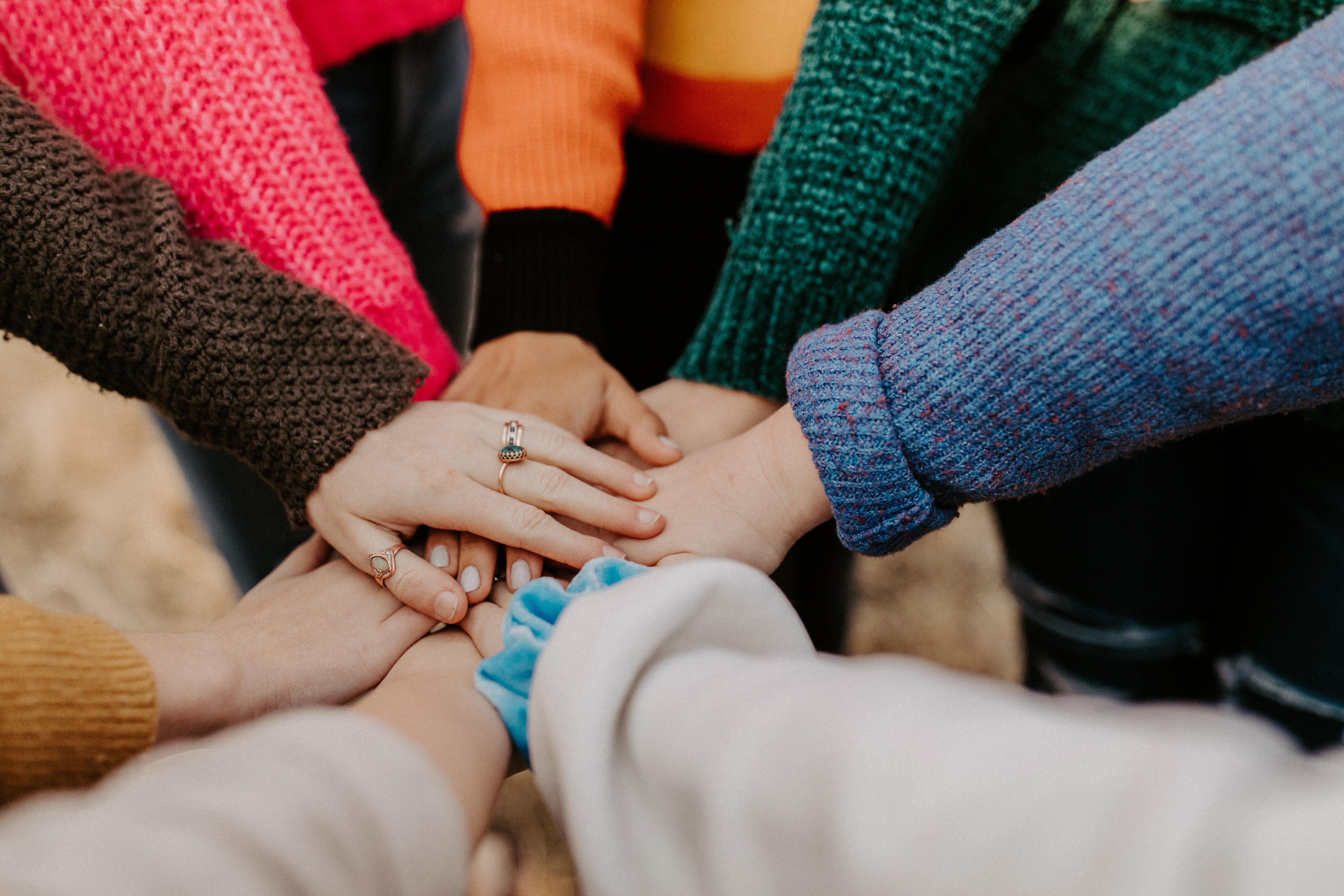 People placing their hands in a circle on top of one another