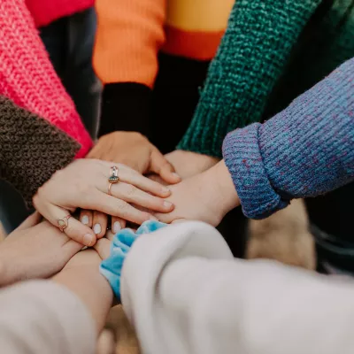 People placing their hands in a circle on top of one another