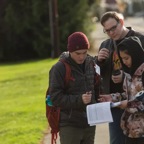 Three people stand around a clipboard