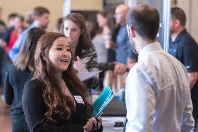 A large room of people in professional attire networking.