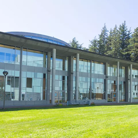 SMATE, a two story glass-fronted building overlooking a lawn.