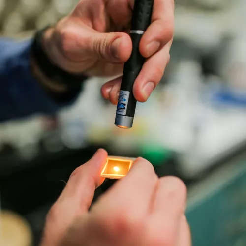 A person shines a laser at a clear surface.