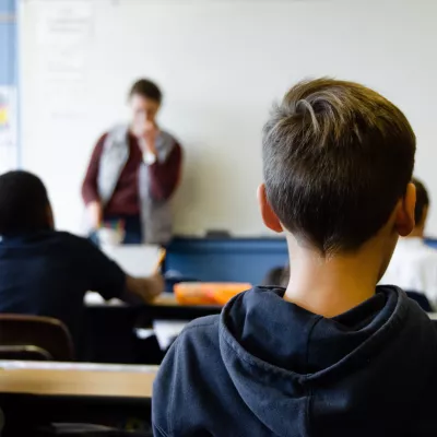 A teacher at the whiteboard in front of a classroom of students