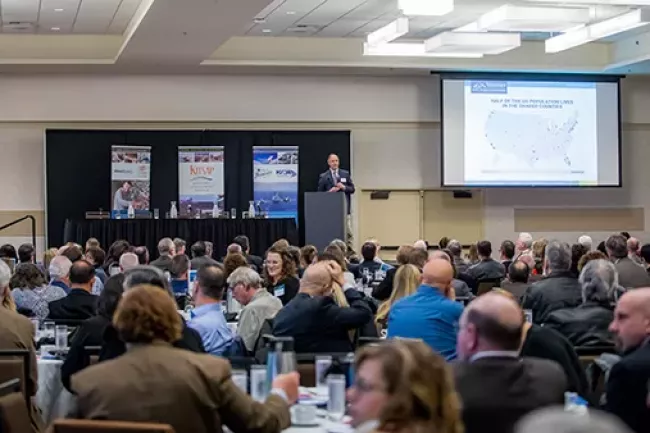 A person presenting at a conference room full of people