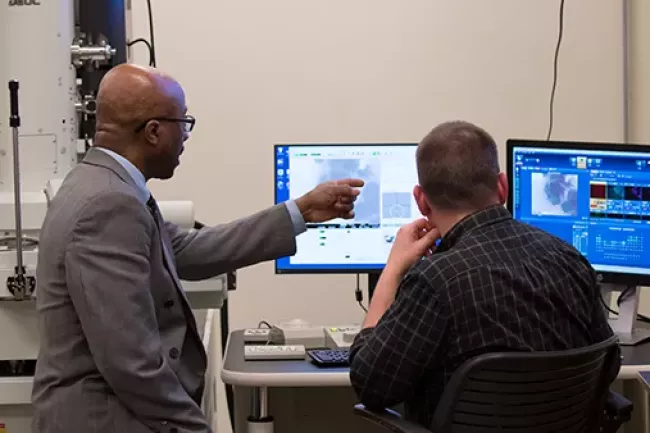 One person pointing out something on a computer screen to another person
